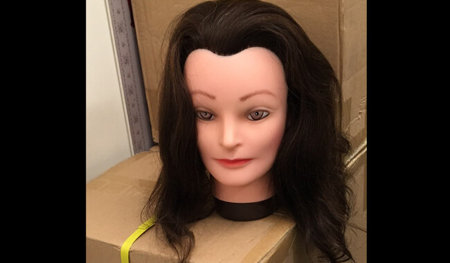 Hairdressing dummy head with dark brown hair.