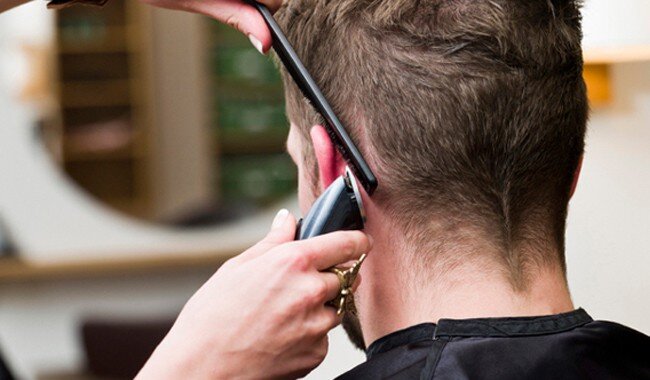 Close-up of a man having his hair trimmed with hair trimmers.